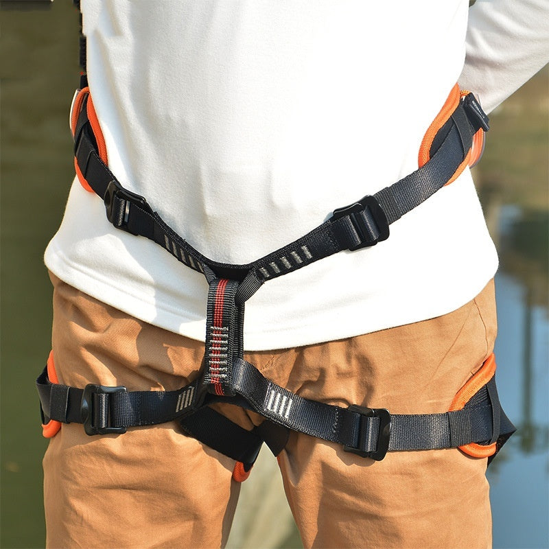 Person wearing a black and orange safety harness with a blurred natural background
