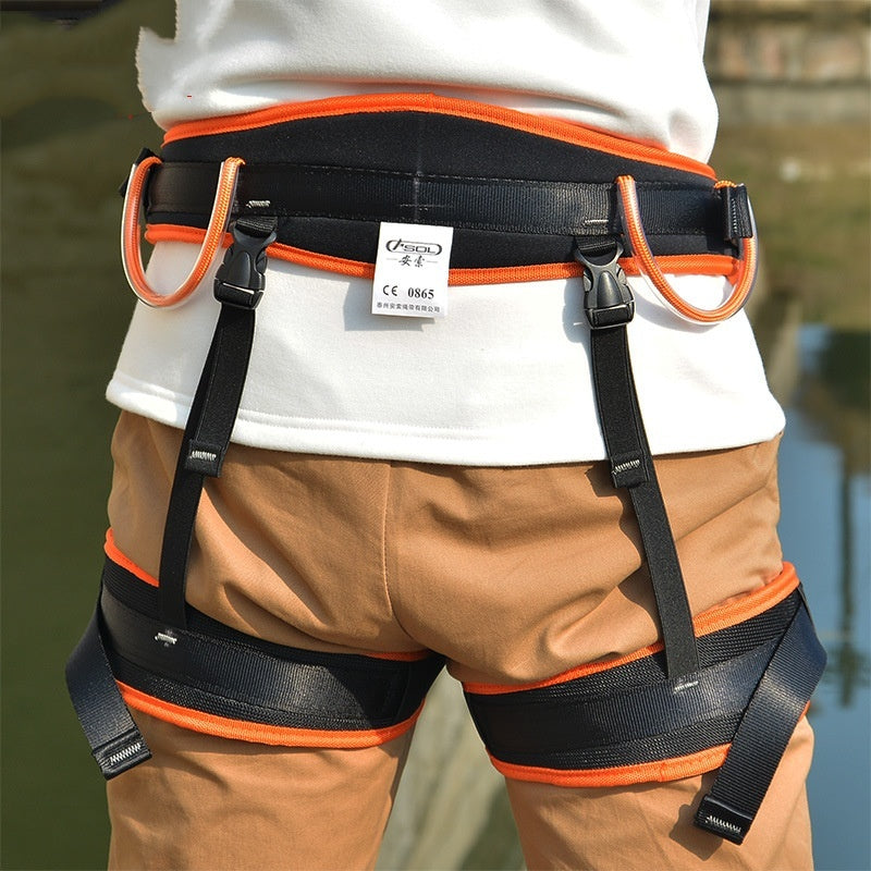 Person wearing a safety harness with orange accents on a blurred natural background
